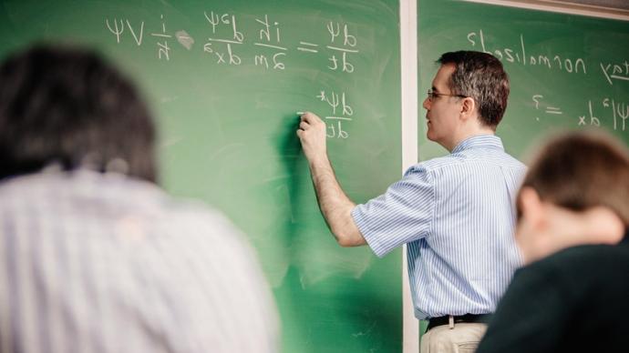 丹尼斯·乌格里尼在黑板上写公式