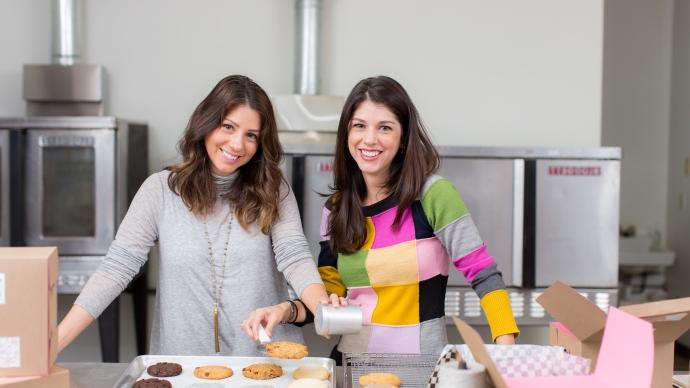 Lauren Swoboda Pepping ’06 (left) and Lyn Swoboda Akhil ’06 (right) smile from the Cookie Cab kitchen.