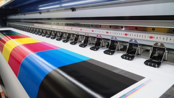 Up close image of the inside of a printer with bright colored ink and white glossy paper