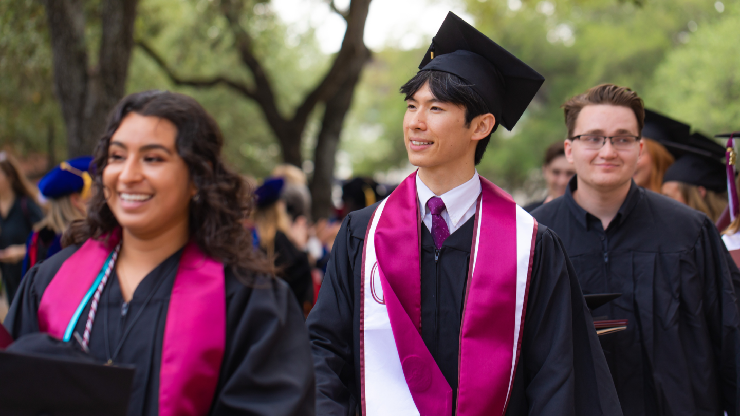 graduates from the Class of 2022 walk by their professors after the Commencement ceremony