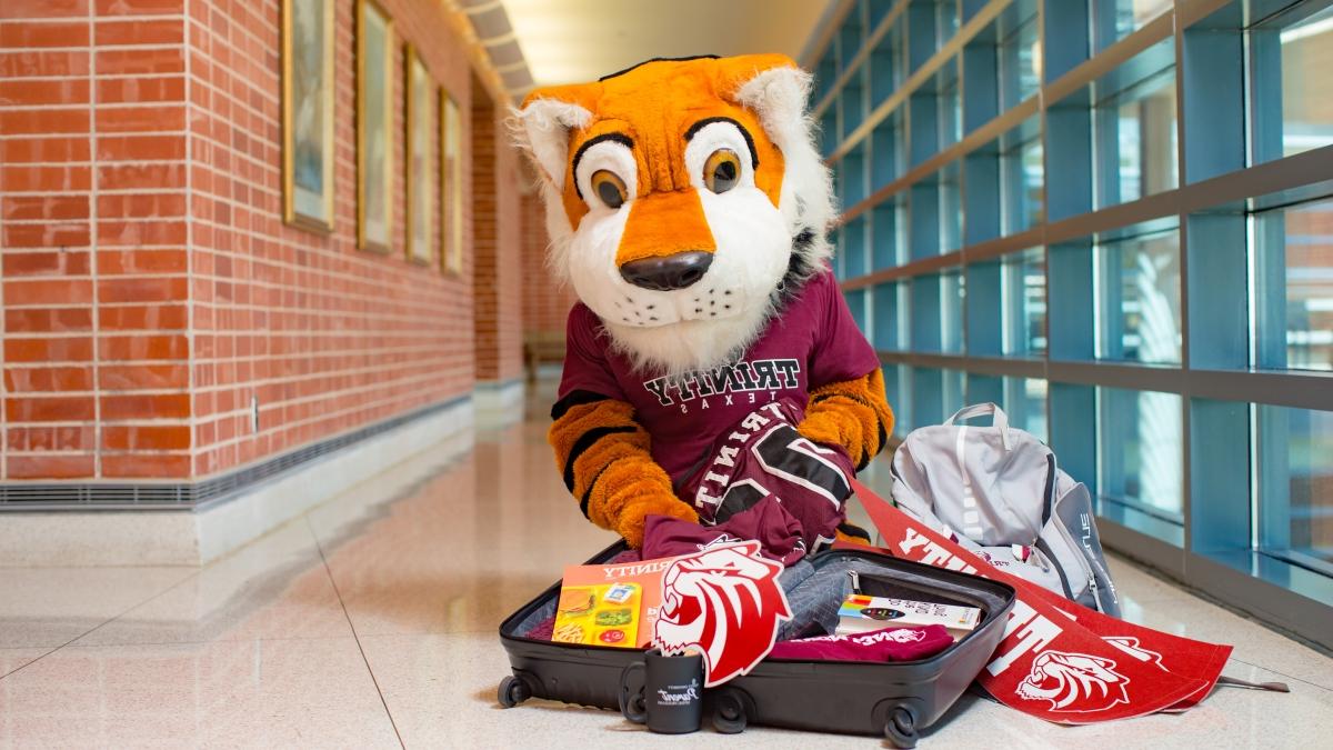 the LeeRoy Tiger mascot poses with an open suitcase full of 澳门金沙线上赌博官网 swag